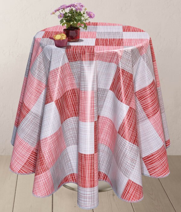 Round table covered with a red, white, and gray checkered wipe clean PVC vinyl tablecloth, adorned with a small vase of purple flowers and a bowl of biscuits